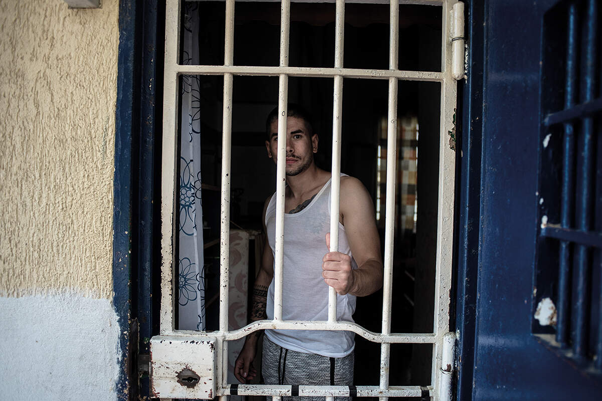 A man holds his cell bars while looking at the camera