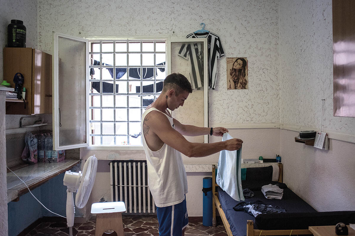 A man folds his clothes in his cell