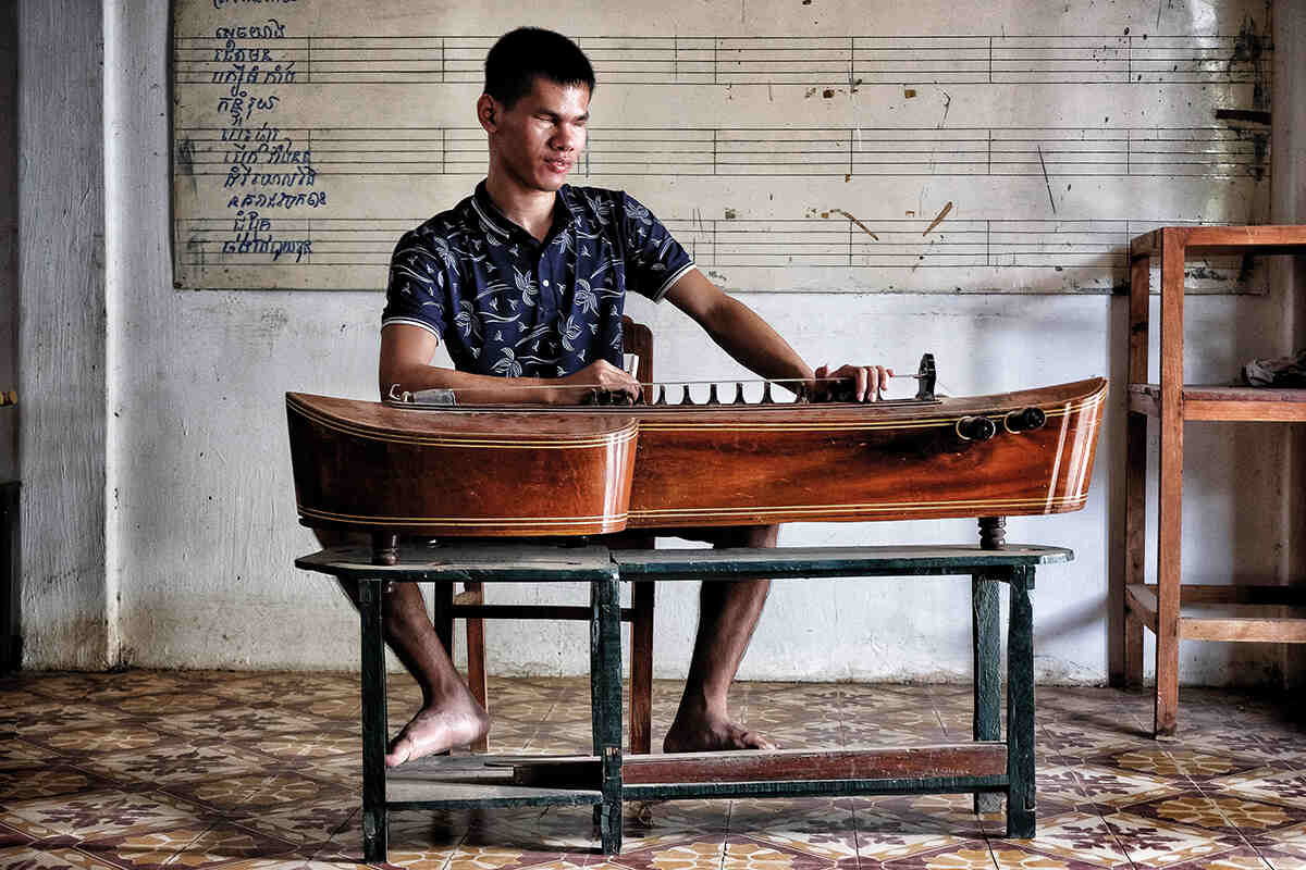 Student sitting down playing a string instrument 