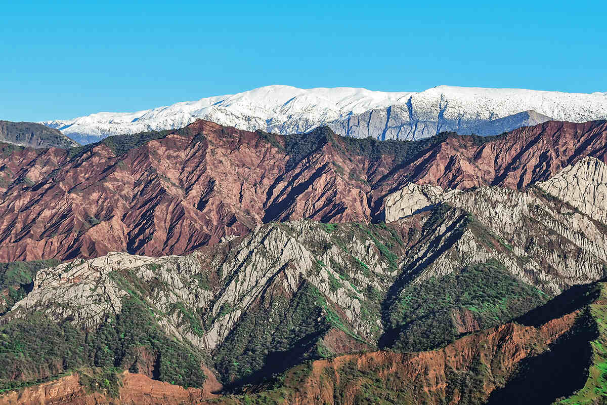 A landscape of red, green snowy mountains