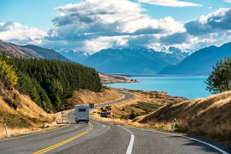 Scenic road trip of Mt Cook or Aoraki over winding road with motorhome driving and Lake Pukaki on sunny day at Peters lookout, New Zealand