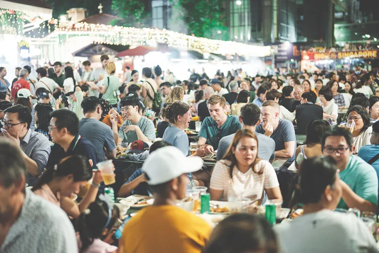 Crowds eating at tables in a busy Singapore food market