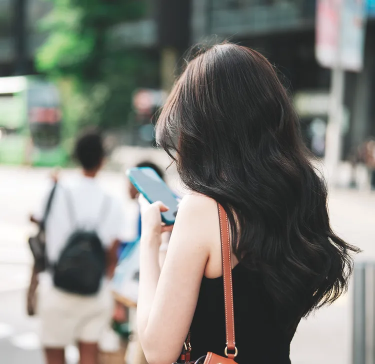 A woman looking at her phone on a Singapore street