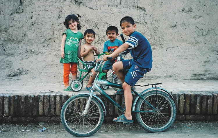 Four children with a bicycle in front of a wall in Uzbekistan