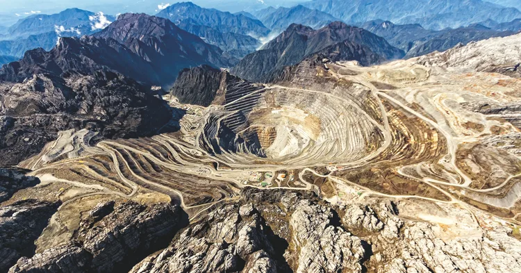 Aerial view of the terraced open pit of the Grasberg gold mine among mountains
