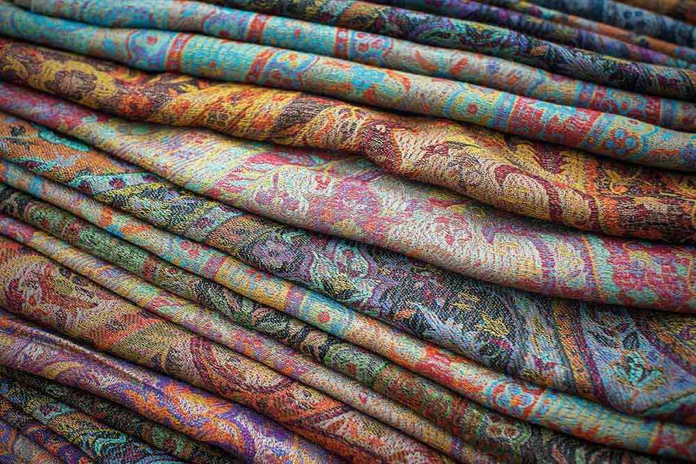 A stack of colourful finished pashmina shawls