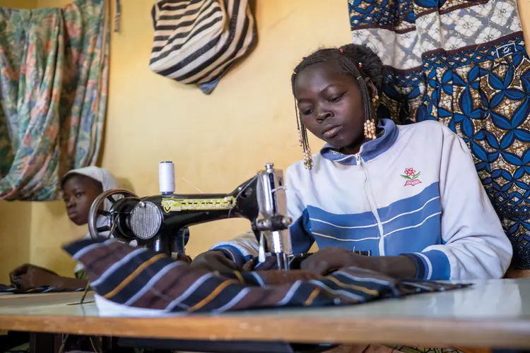 A teenager, Scholastique, sewing using a sewing machine.