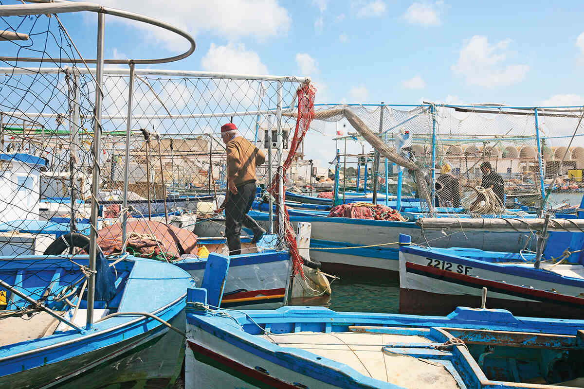 A man walks on Artisanal boats in Sharqi Island’s harbour