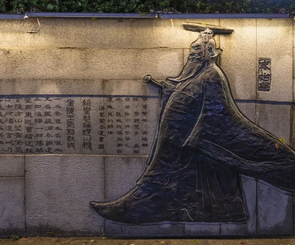A bronze memorial of Qin Shi Huang, lit by a an overhead lamp.