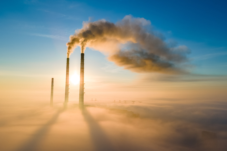 Aerial view of coal power plant high pipes with black smoke moving up polluting atmosphere at sunset