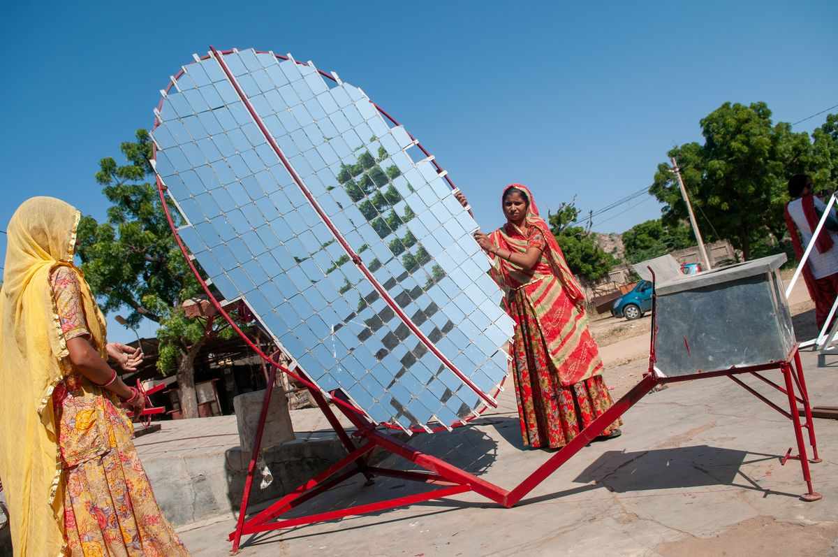 Women setting solar-powered cookers