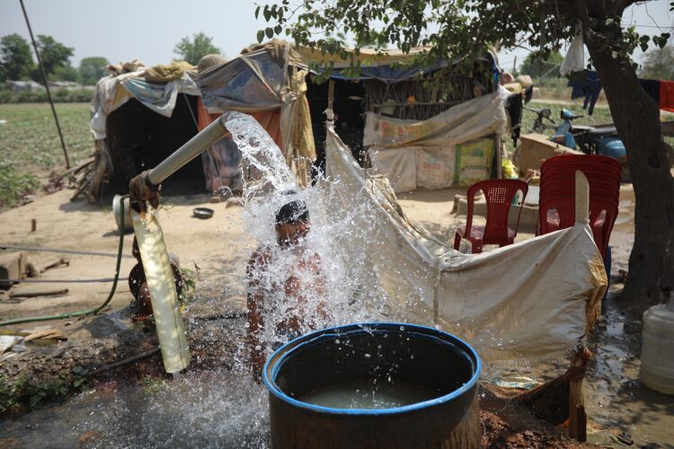 A boy cools himself off at a tube-well near a field amid rising temperature due to global warming in New Delhi