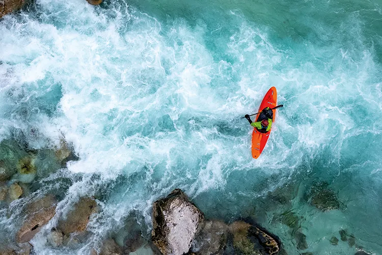 A man goes down white water rapids in a canoe