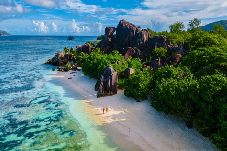 Anse Source d'Argent beach, La Digue Island, Seychelles, couple men and woman walking at the beach during sunset at a luxury vacation in the Seychelles