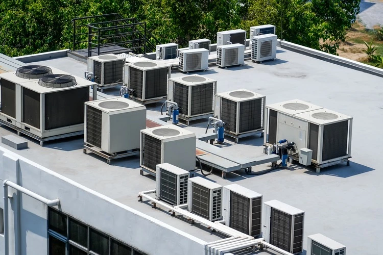 The external units of the commercial air conditioning and ventilation systems are installed on the roof of an industrial building.