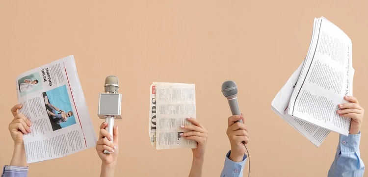 Female hands with microphones and newspapers on beige background