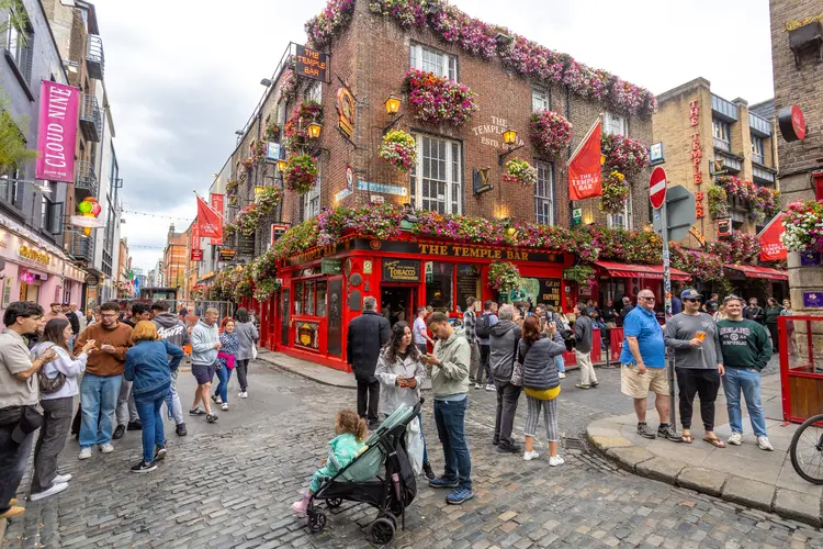 Dublin, Ireland, July 5, 2024: Tourists gather on the street outside the famous The Temple Bar Pub, capturing photos and enjoying the vibrant atmosphere.