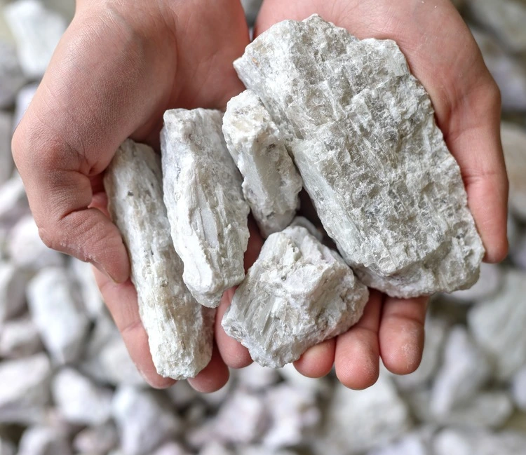 Hard rock spodumene ore, commercially important source of lithium. Mine, mining. Held in human hand. Copy space.