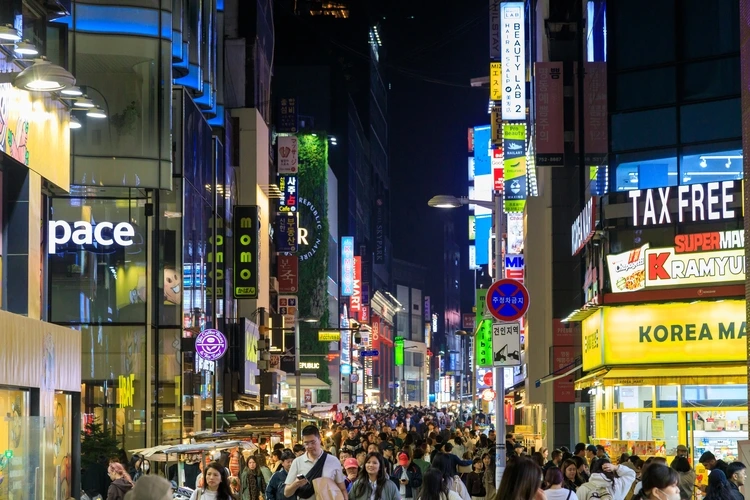 Seoul, South Korea - Street scene of the bustling and vibrant shopping district Myeong-Dong at night with illuminated signs.