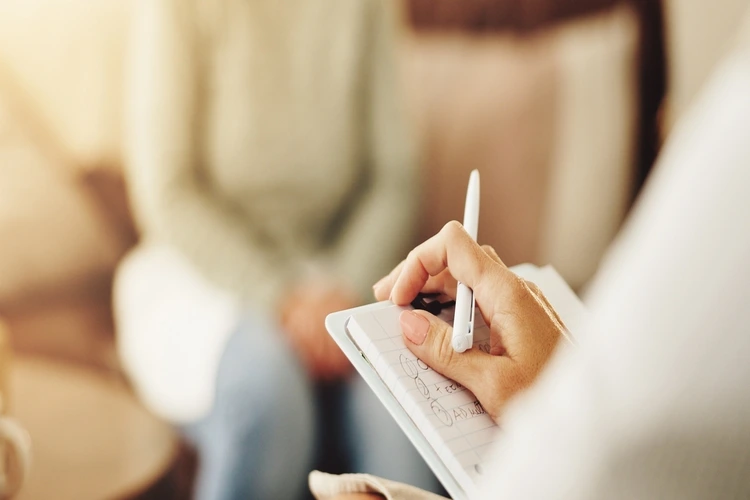 Clipboard, patient and hands of therapist in office for mental health, depression or anxiety checkup. Medical report, checklist and closeup of psychologist with notes for counseling session at clinic