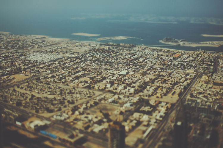 True tilt shift shooting from top of Dubai: residential buildings, highways and coastline with sea and islands, sunny summer day