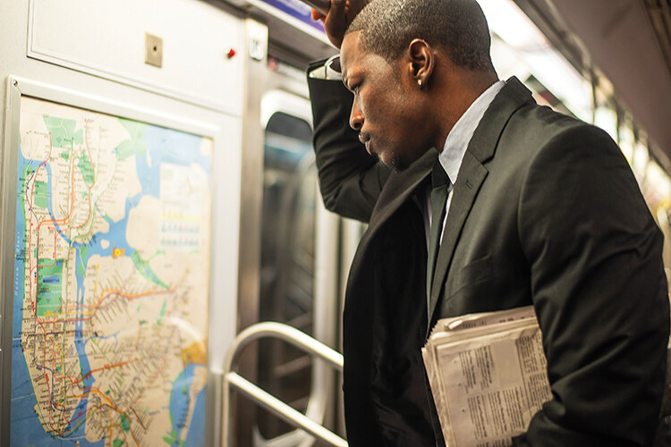 A man in a suit looks at new york subway map on a train