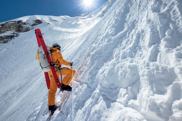 Jim Morrison carrying skis on the snowy slopes of Mount Everest