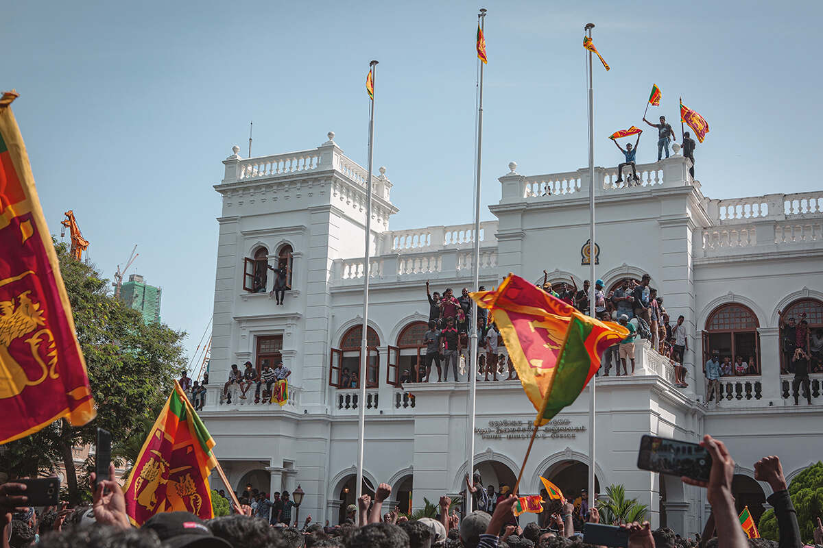 Protesters sit outside and stand atop sri lanka's parliament building in july 2022