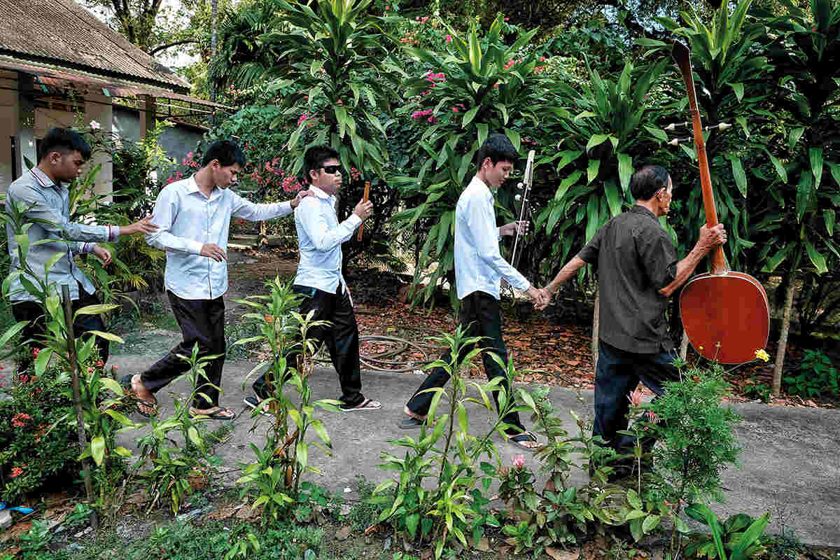 Four students walking down a path led by their teacher