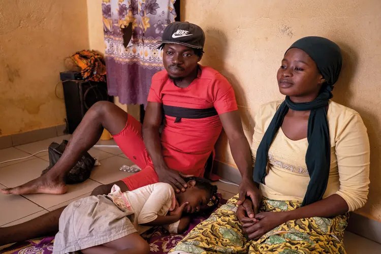 Thérèse and her husband, Osmand, sit together on a floor with their four-year-old daughter Fadila.