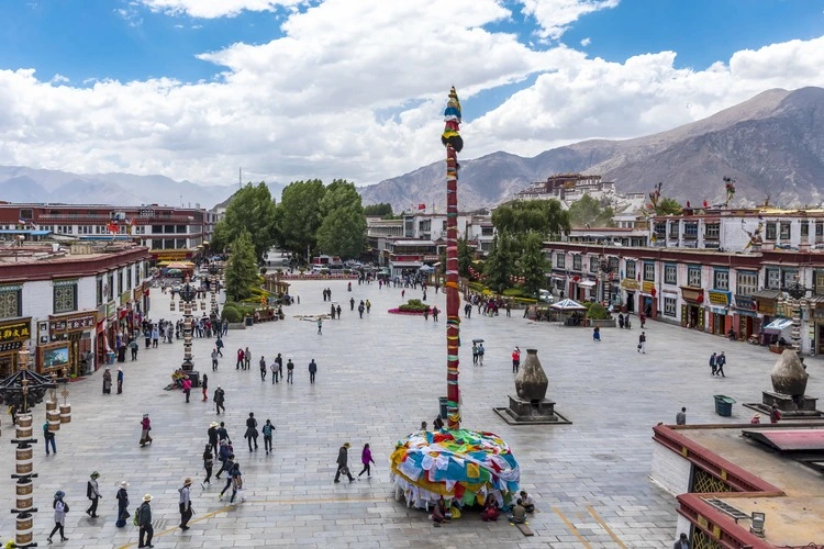 Wide angle and spring view of tourists on the square with a tower among the buildings of Jokhang temple