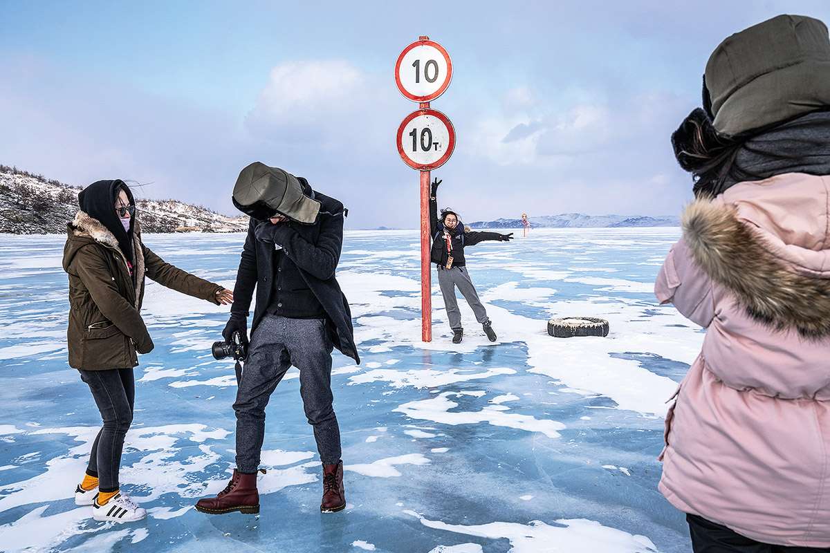 Four figures stand next to a sign on the frozen lake