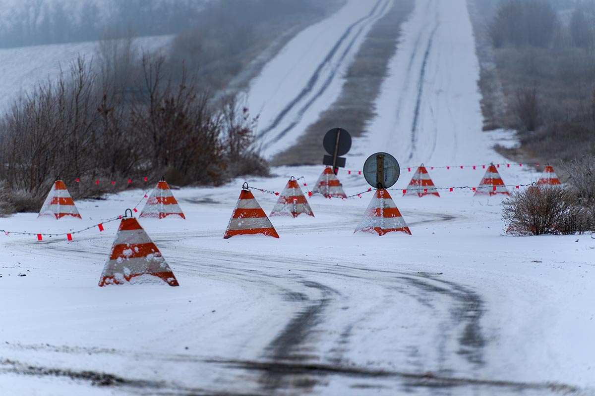 Orange bollards forming a roadblock on a snowy road in Eastern Ukraine