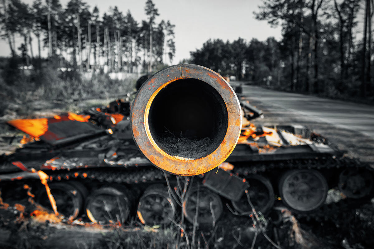 Black and white photo of a coloured rusted tank barrel pointing at camera in a forest