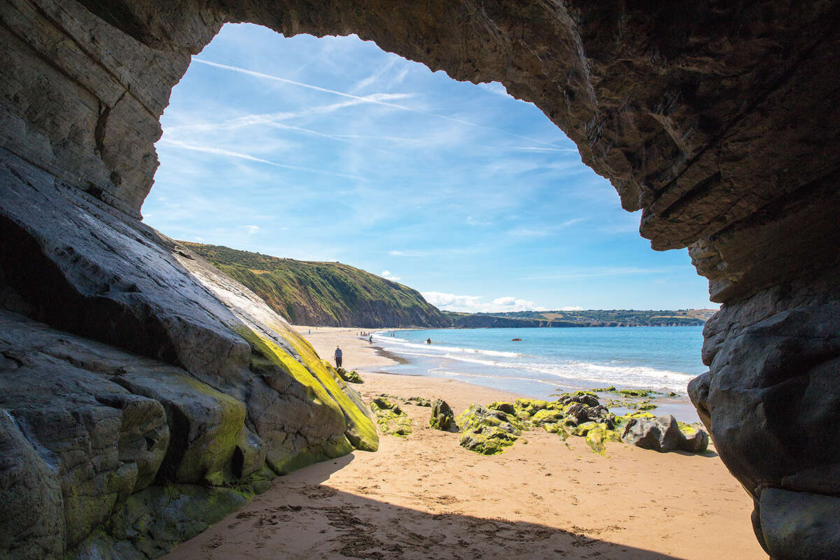 A view of cardigan bay, Wales from inside a hole in the rocks with blue skies