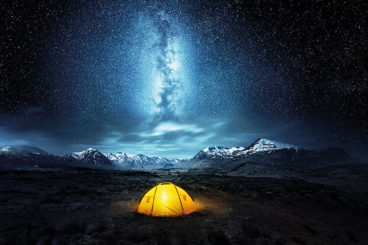 A yellow tent under stars with mountains