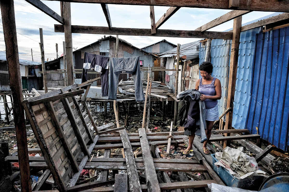 Gay Baliña, 45, collects laundry from a makeshift clothesline in a part of her house in Surigao that she has not yet been able to rebuild