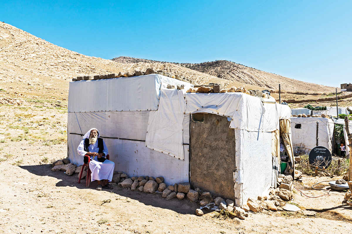 An elderly Yazidi man sits outside his shelter in the desert