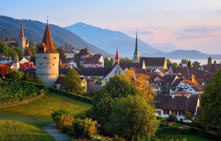 View of Zug city's medieval Old town and surrounding swiss Alps mountains in sunset light, Switzerland